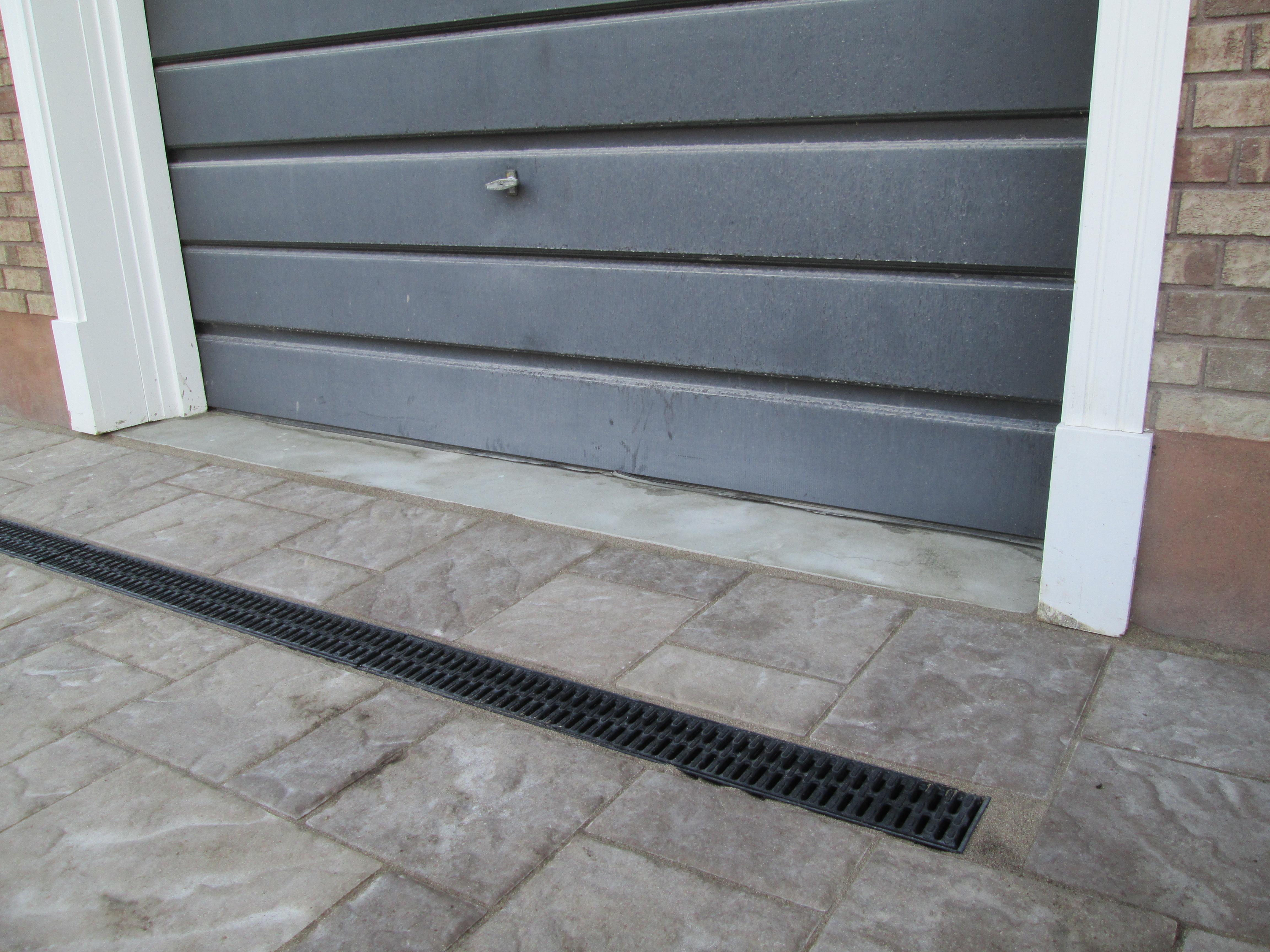 Image 9 : le nouveau dallage et la grille du nouveau drain près de la porte du garage